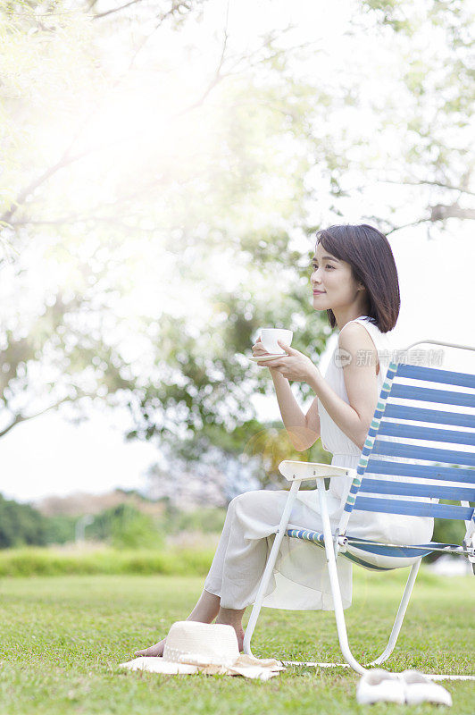 年轻女人坐在躺椅上喝茶 咖啡